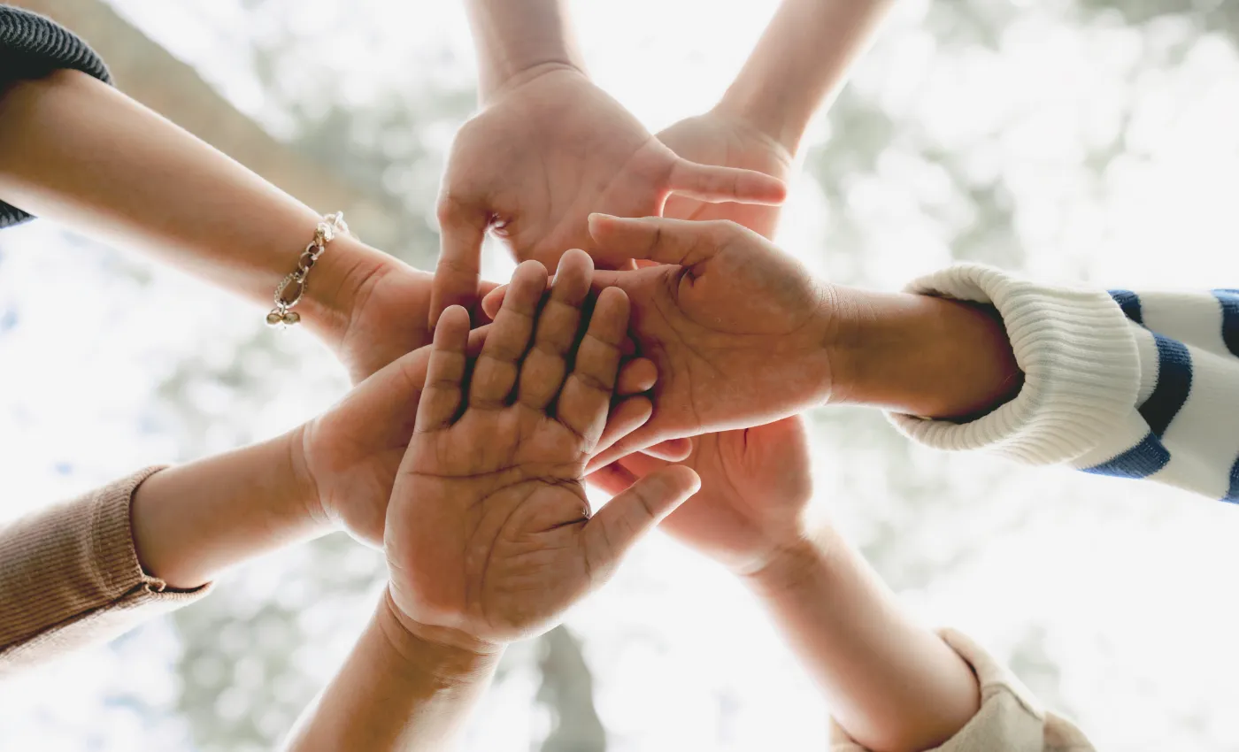 Gemeinschaft und Zusammenhalt symbolisiert durch verbundene Hände Verschiedene Hände, die gemeinsam einen Kreis bilden